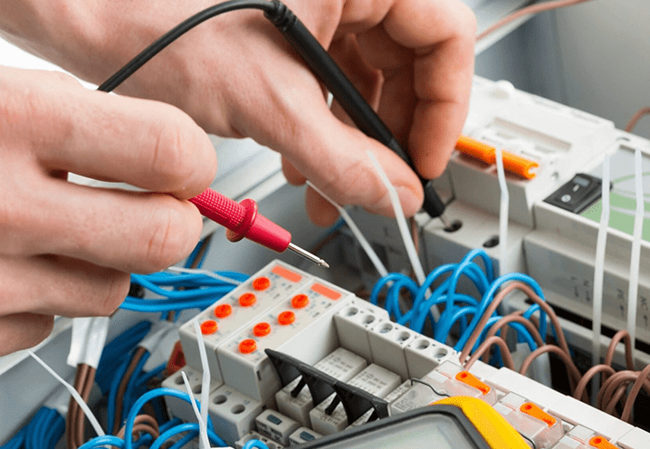An electrician's hand repairing fault from a bunch of electrical wires with a screwdriver